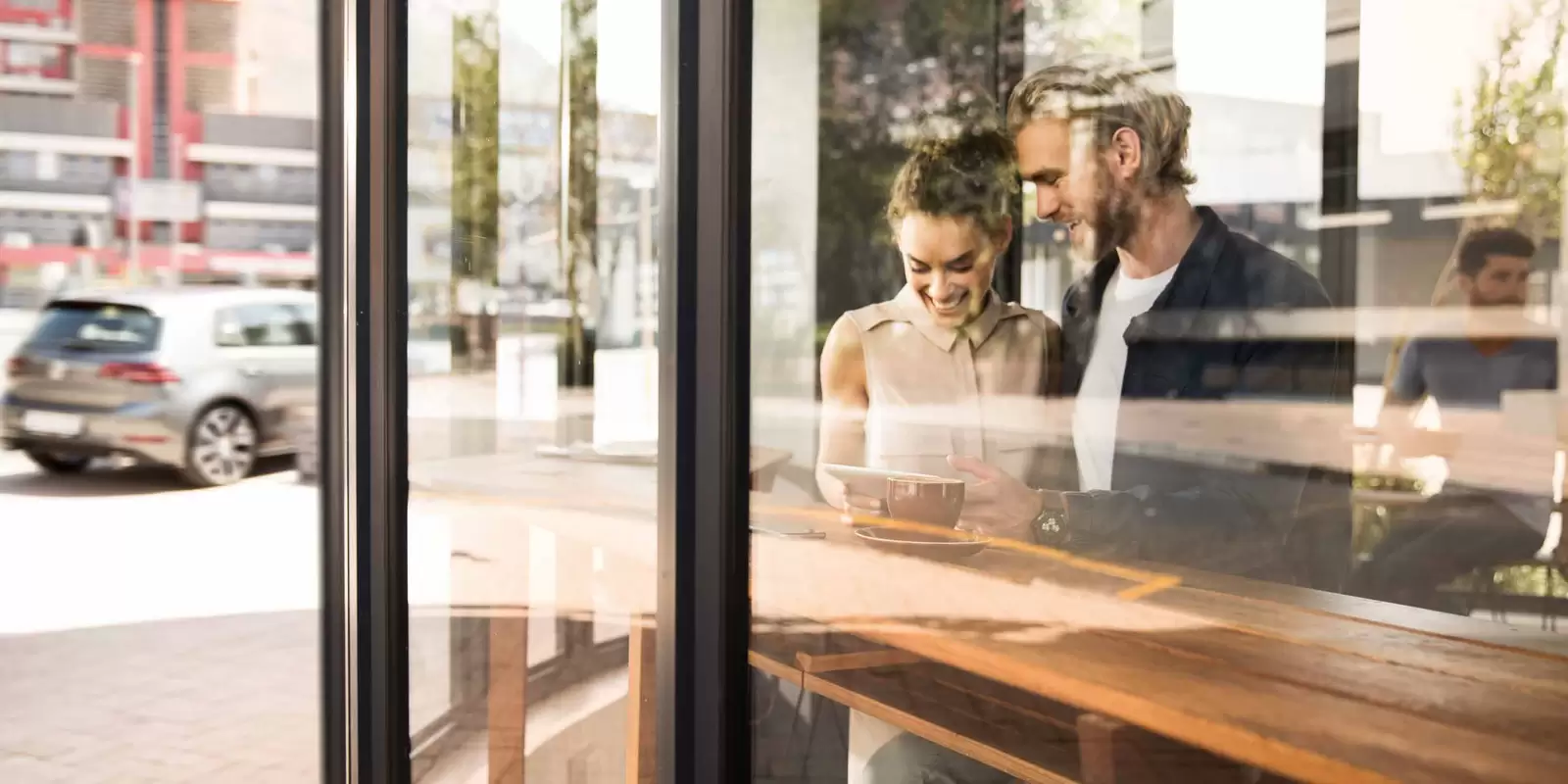 Seguro GAP: mulher e homem olhando para um tablet numa cafeteria