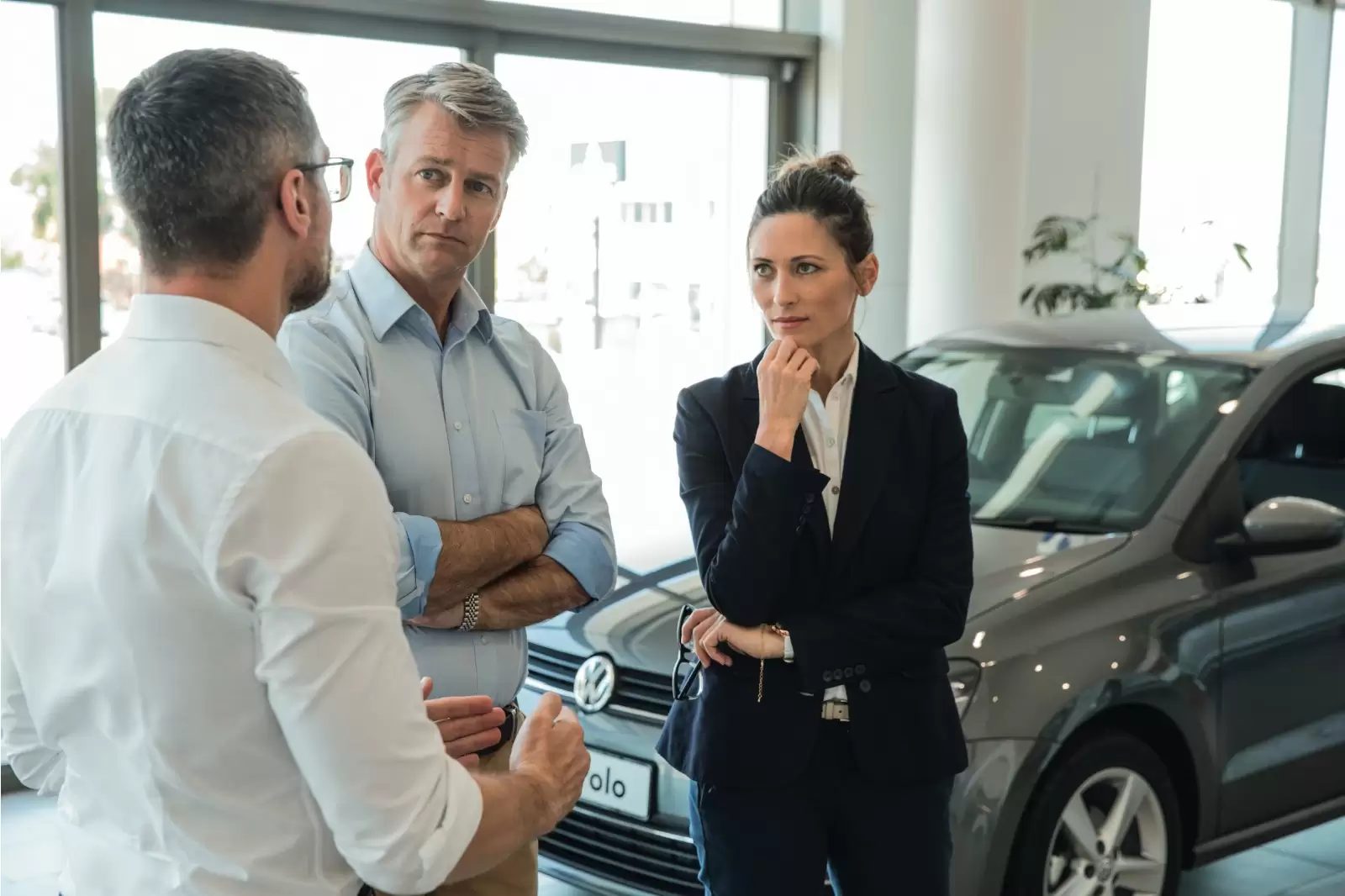 Financiamento Fácil Volkswagen: dois homens e uma mulher em frente a um Polo