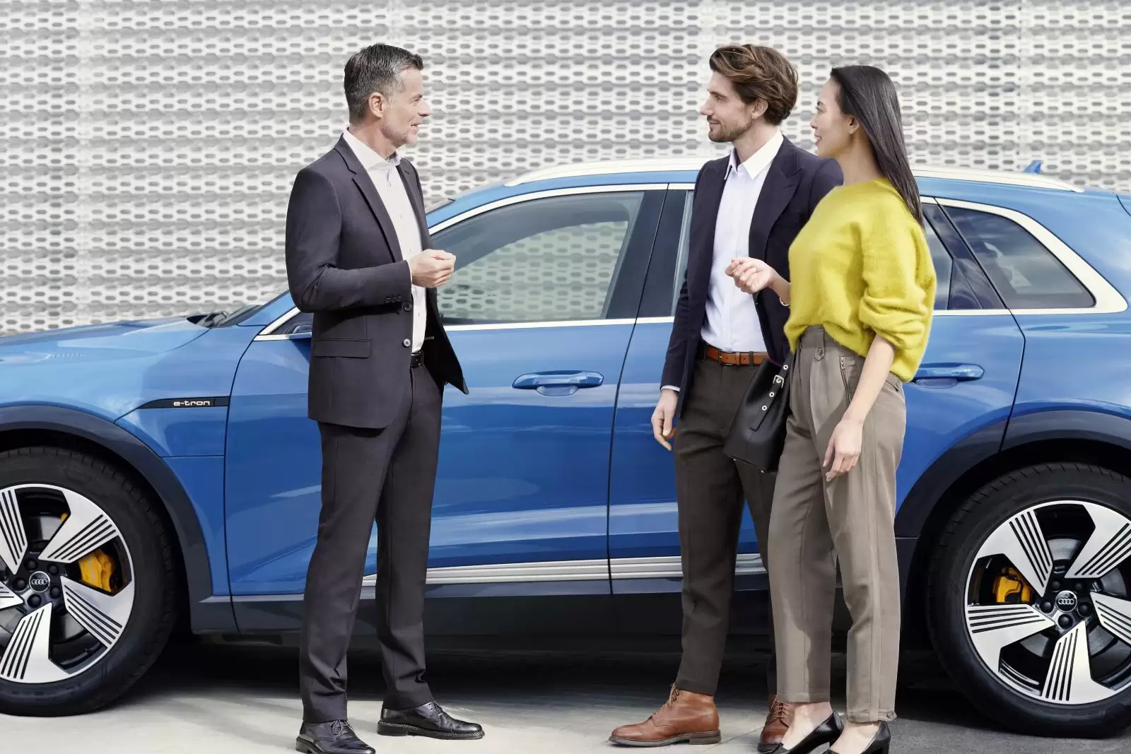 Loja Online Audi: 3 pessoas conversando na frente de um carro azul