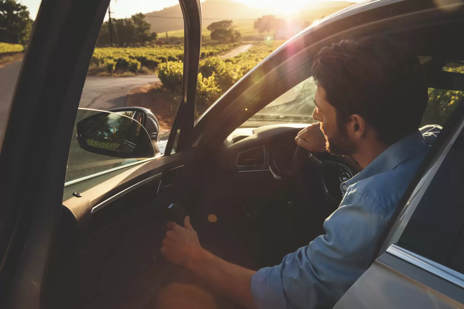 Seguro de Acidentes Pessoais Volkswagen: homem dentro de um carro, com a porta aberta, olhando para o horizonte.