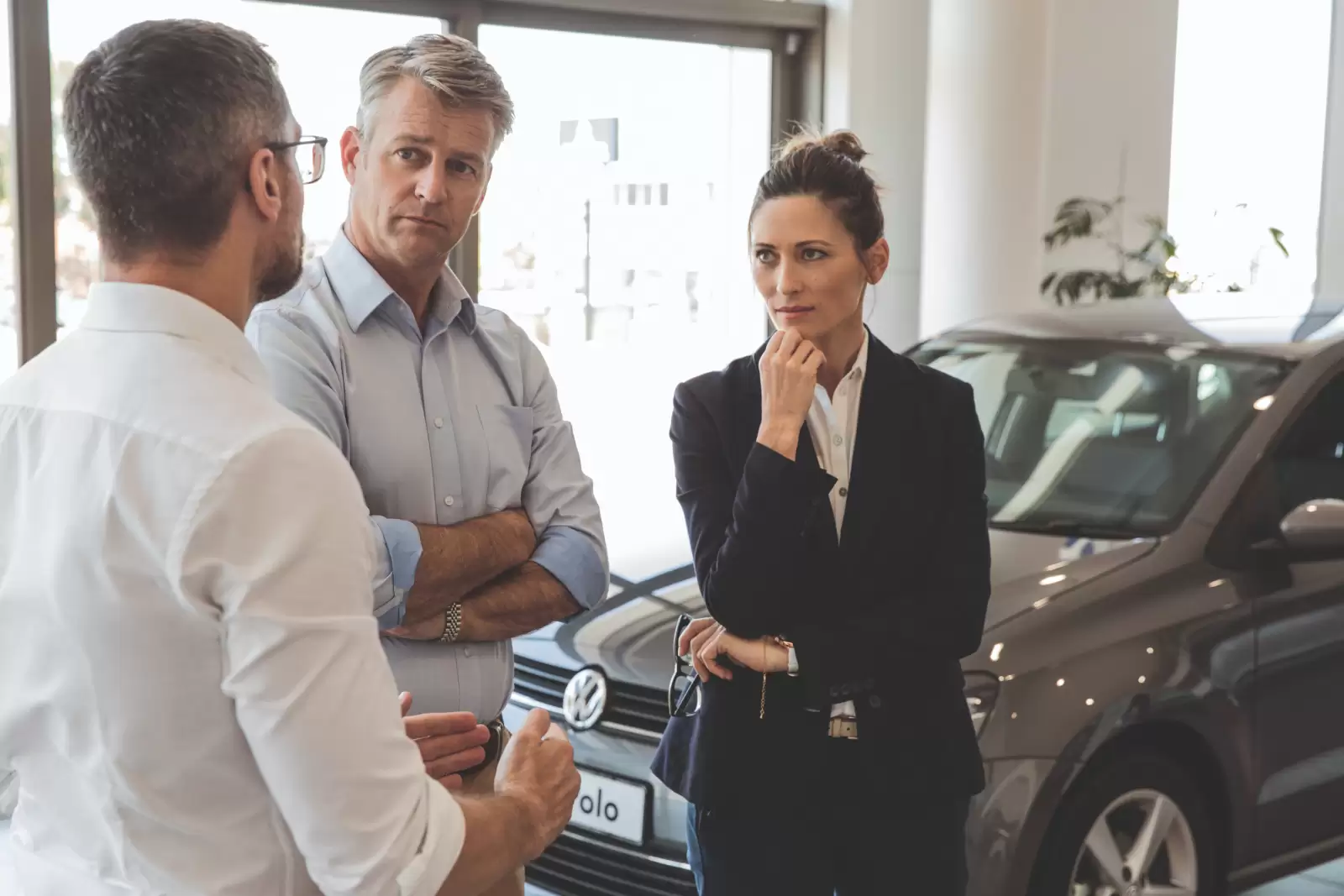 Seguro de Acidentes Pessoais Volkswagen: três pessoas conversando em frente a um carro. 