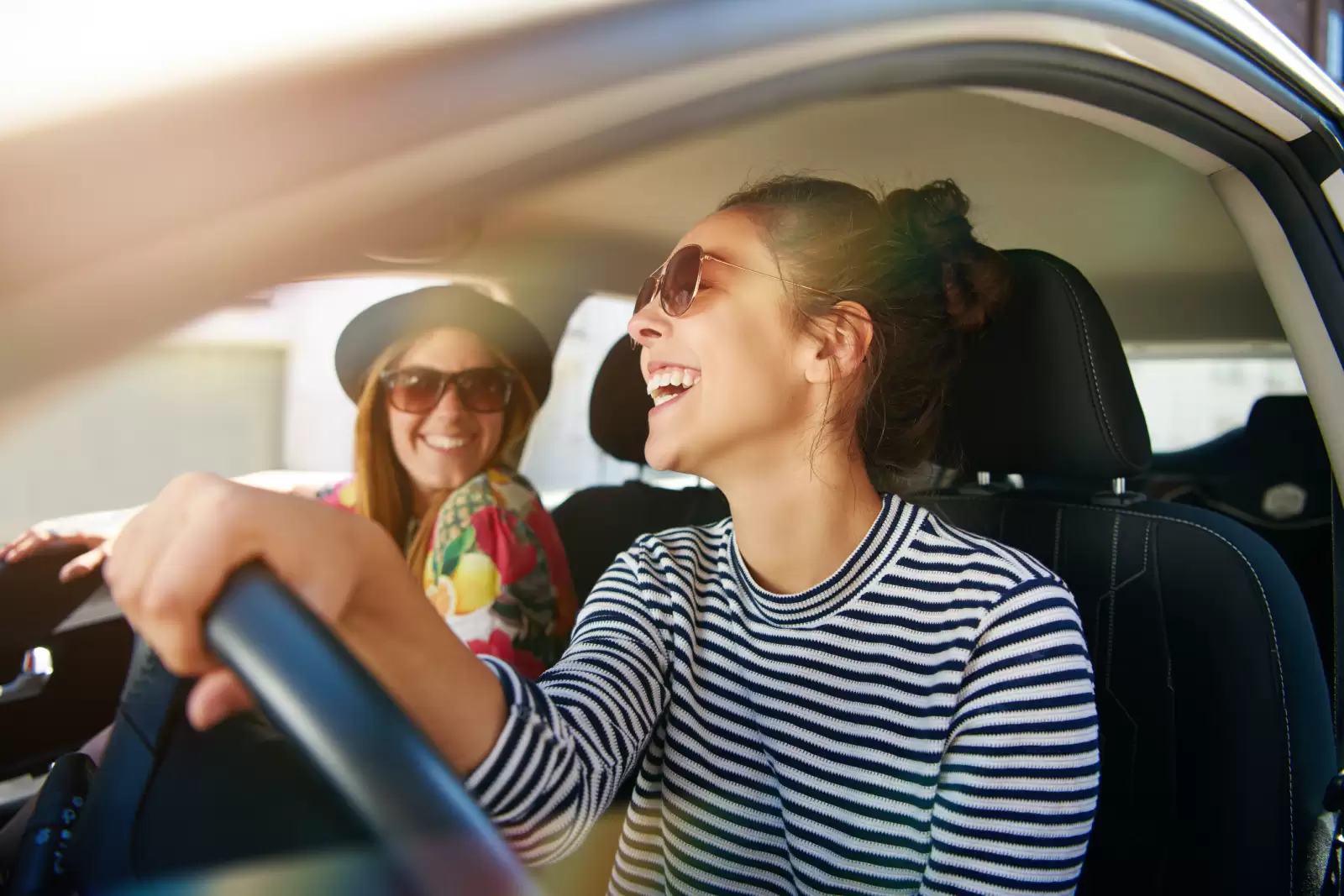 Seguro Garantia Estendida Volkswagen: duas mulheres dentro de um carro sorriem enquanto uma delas dirige.