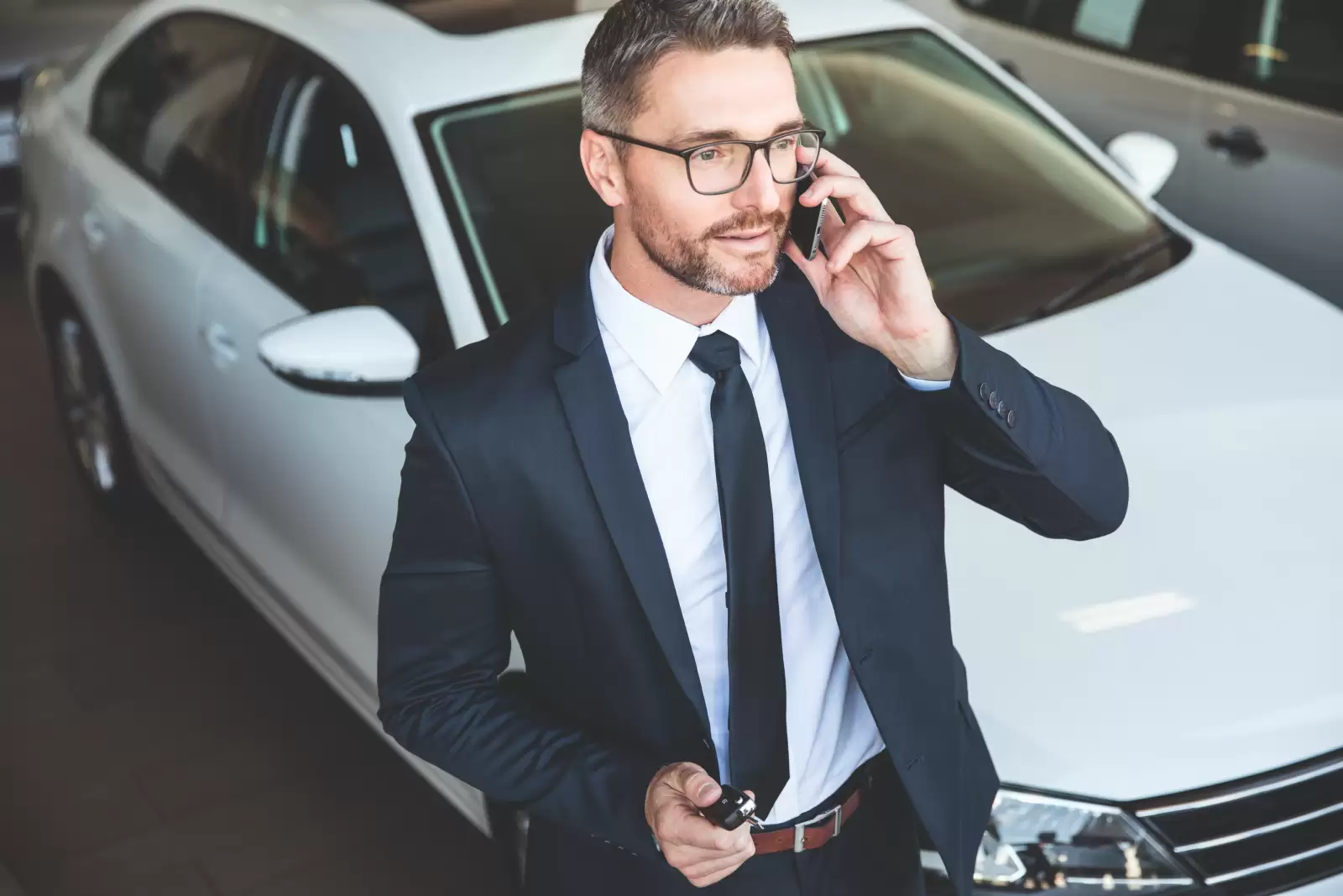 Revisões Planejadas Volkswagen: homem falando no celular em frente a um carro branco. 