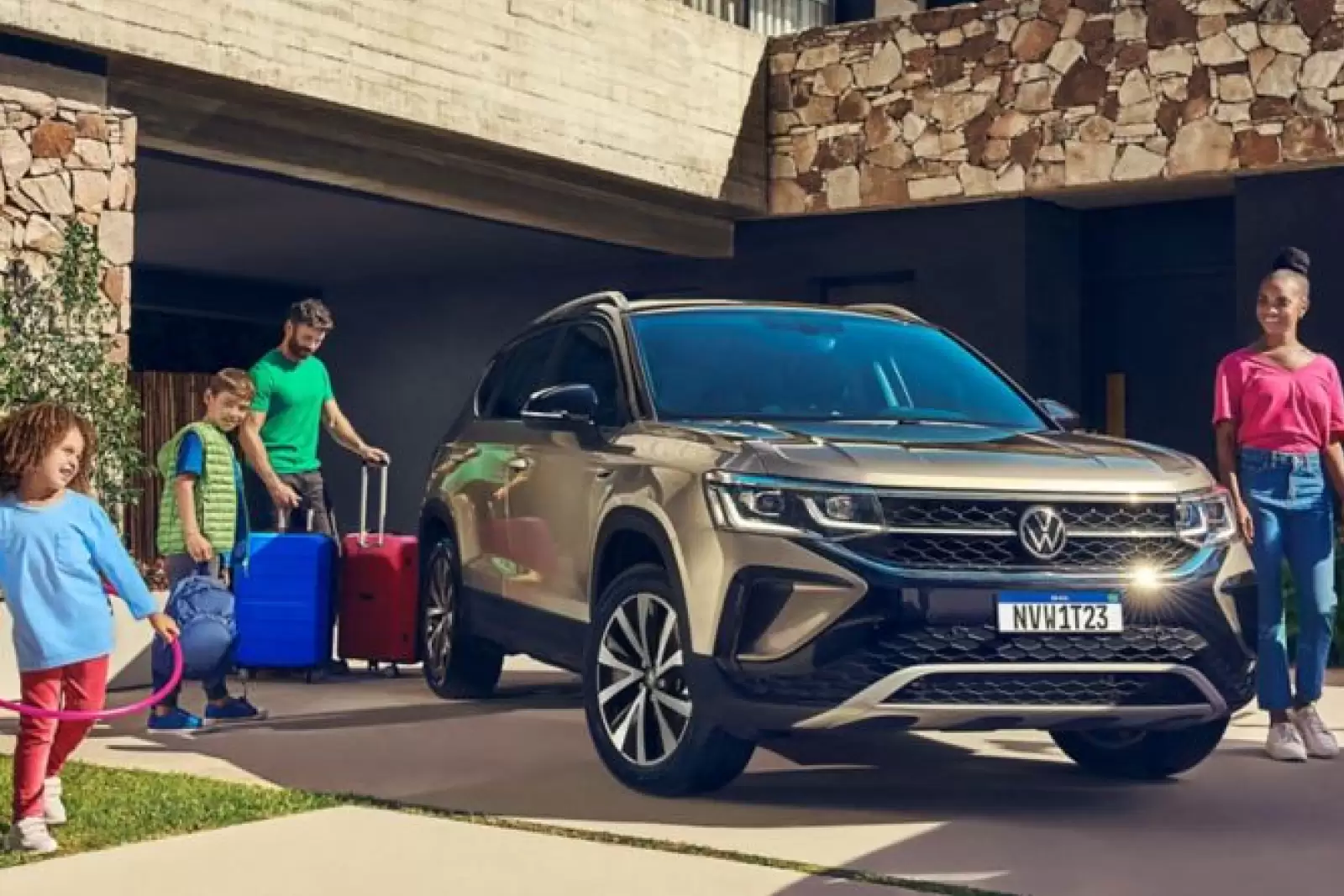 Seguro Volkswagen: uma família, composta por um homem, uma mulher e duas crianças, colocando a bagagem no carro que está ao centro da imagem. 