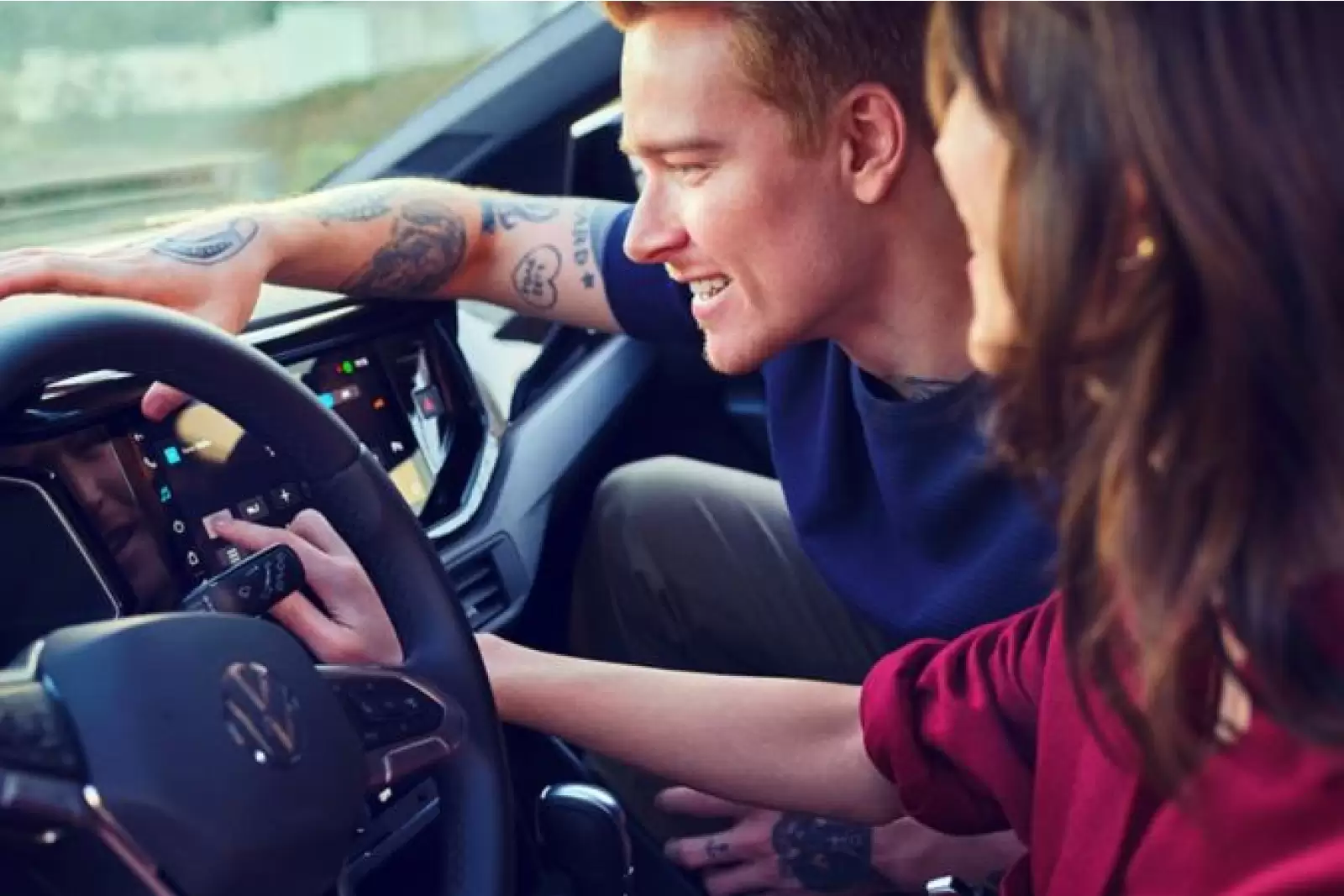 Seguro Volkswagen: uma mulher e um homem configurando o painel digital de um carro.