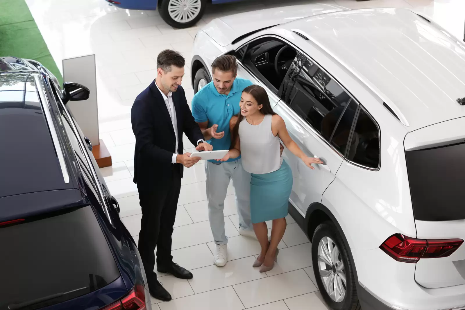 Seguro GAP Volkswagen: três pessoas conversando em uma concessionária enquanto olham o que uma delas está mostrando em um tablet. 